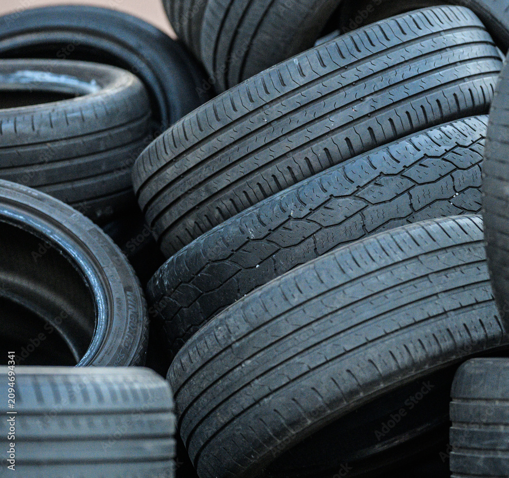 Obraz premium Close view of stacked discarded tires with chalk markings.