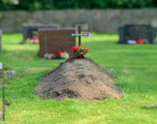 Fotografía Fresh grave mound with flowers and cross in cemetery.