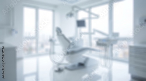 Blurred interior view of a modern professional dental clinic with medical equipment and bright clinical lighting