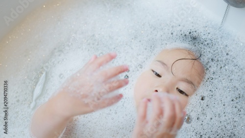 Tableau sur toile A serene young Asian child unwinds in a sudsy bubble bath, a quiet moment of sensory play and wellbeing as part of a daily home hygiene routine