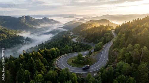 Winding mountain road through lush green forest. Curving highway cutting through dense woodland at sunrise. Scenic travel route for adventure and e...