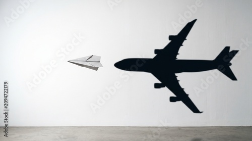 Paper plane casting a large airplane shadow