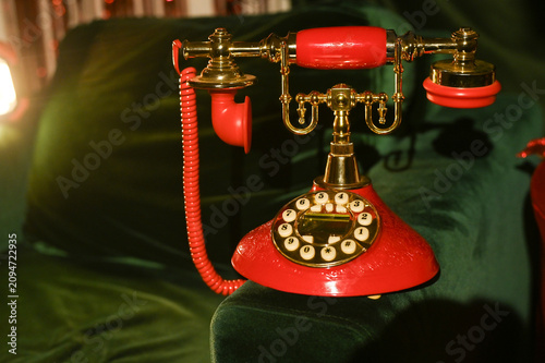 Foto red rotary phone with brass elements, placed on a velvet green surface
