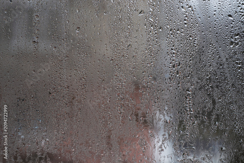 Quadro su tela Wet glass with dense raindrops and vertical water lines