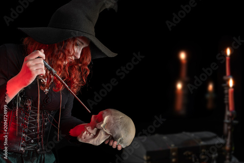 Fotografía Witch with a magic wand and a skull casts a spell