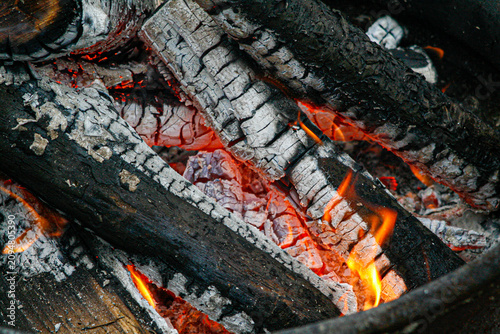 Photography Close-up of glowing embers and charred logs in a dying campfire