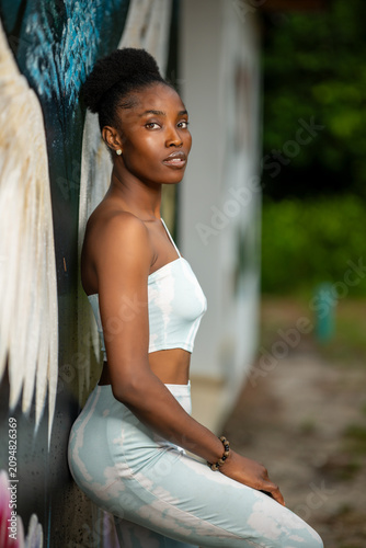 Portrait of a young African woman leaning against a wall