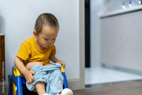 Fotografie Asian toddler sitting on potty chair at home