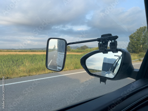 Tow car mirror reflecting caravan on a road