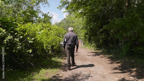 Elderly man with a newspaper walking down a forest trail promoting active aging and mental health in older adults