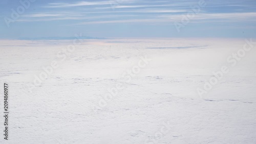 Airplane window view flying over a sea of clouds during commercial air travel and tourism