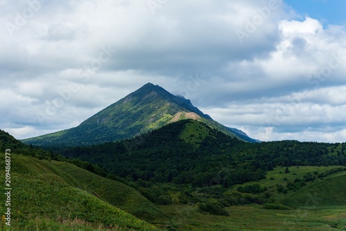 Foto A striking landscape featuring a prominent, forested mountain with exposed rock