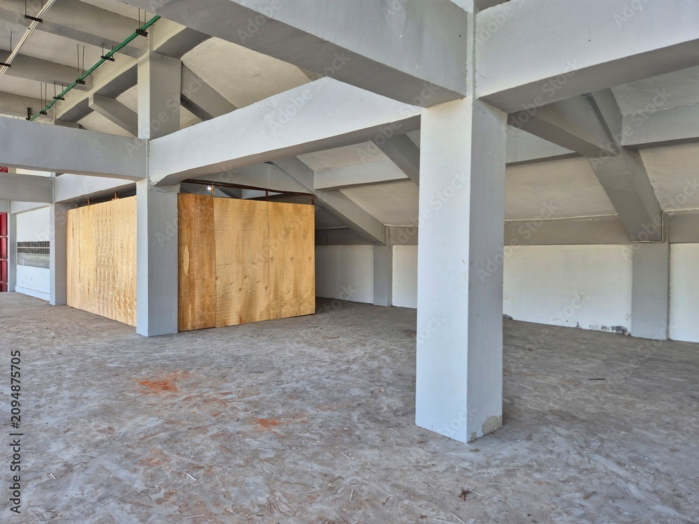 Obraz premium Interior concrete ceiling with exposed utility pipes and structural beams in an unfinished industrial building