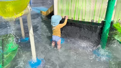 Toddler playing at a colorful splash pad