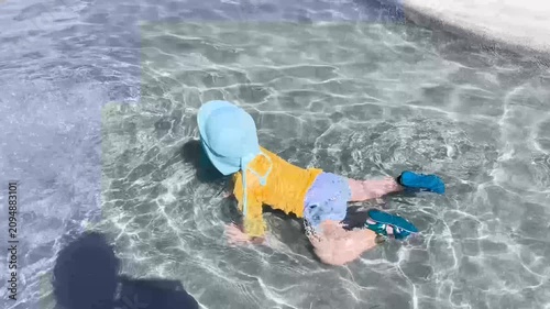 Toddler crawling and playing in a shallow swimming pool