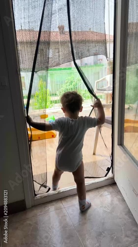 Toddler boy opening magnetic screen door and walking outside