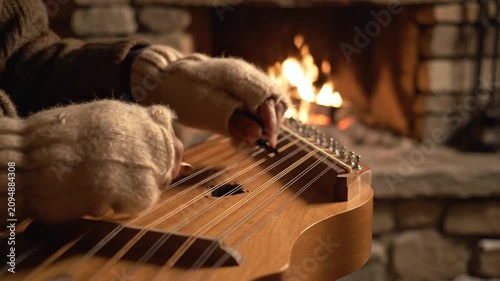 Cozy winter evening: playing a dulcimer by a warm fireplace