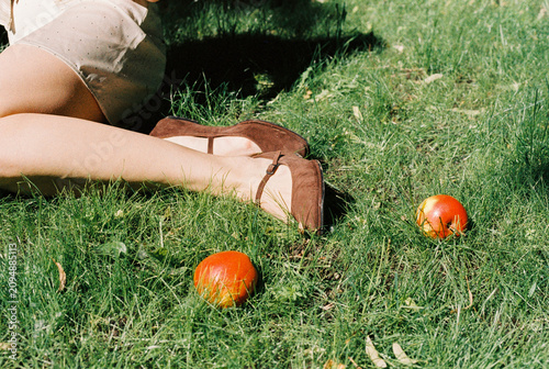 Bare legs and brown suede shoes stretch out among ripe apples
