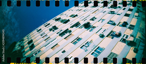 an apartment block rises diagonally in a panoramic image, 35mm film