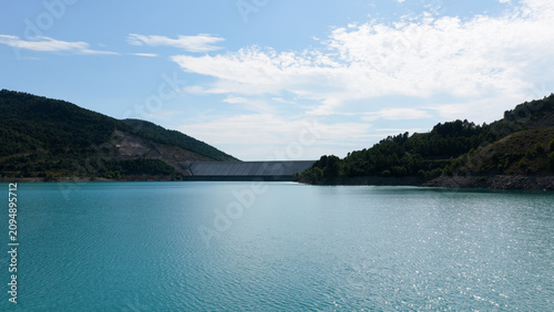 Yesa reservoir, a large dam and turquoise water creating an impressive landscape in the Pyrenees mountains on a sunny day