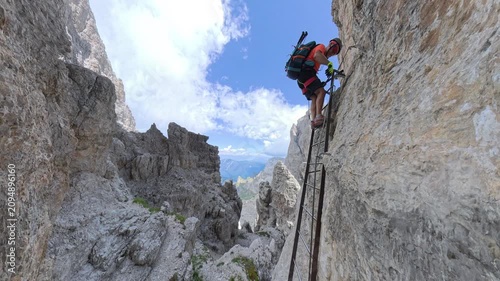 Hiker descending an iron ladder on Via Ferrata Bocchette Centrali, Brenta Dolomites, Italy