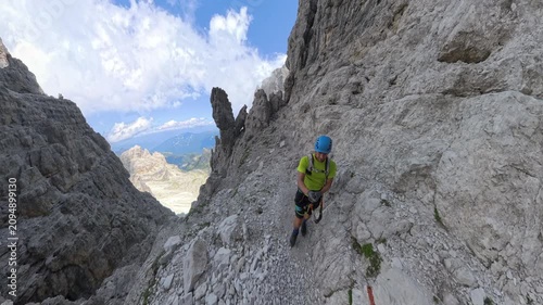Hiker walking between the towering spires of Via Ferrata Bocchette Centrali, Brenta Dolomites