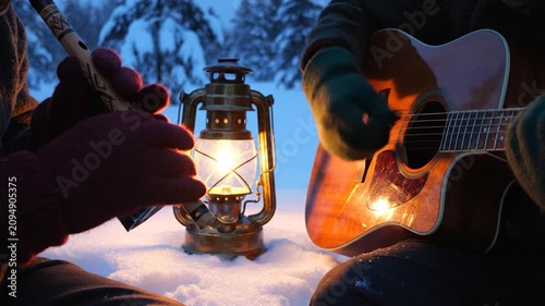 Couple playing music by lantern in snowy winter forest