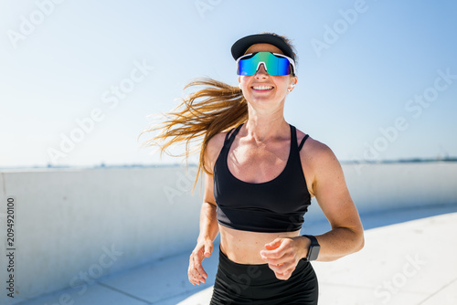 Bright sunshine inspires a joyful run along the urban landscape with a spirited woman embracing fitness and freedom