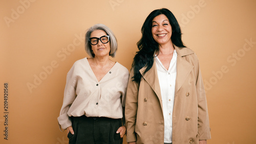 Bild auf Leinwand Two smiling mature women standing side by side, showcasing companionship, confid
