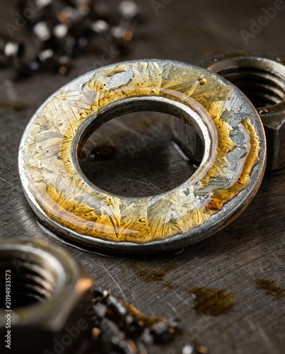 Exquisite editorial macro shot of a crystalline galvanized steel washer coated in amber oil, capturing the pinnacle of metallurgy and high-end industrial design.