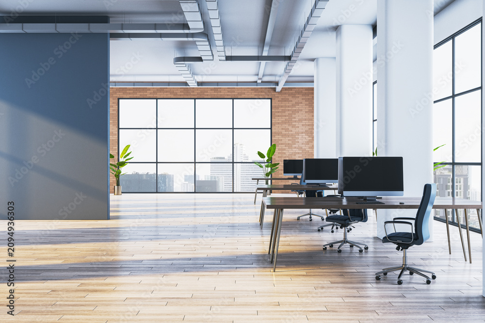 Obraz premium Bright open plan coworking office interior with wooden floor, computer monitors on shared desks, blue wall and panoramic city view windows. 3D Rendering