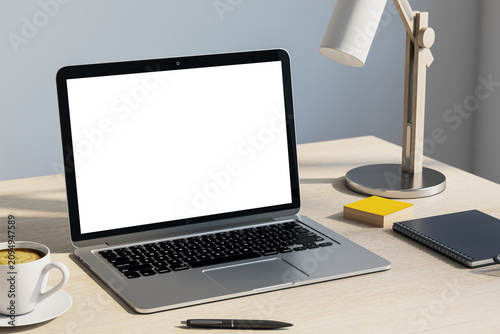 Laptop mockup with blank white screen on wooden office desk with lamp, coffee...
