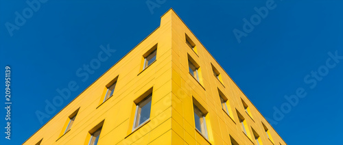 Modern yellow building corner against a clear blue sky