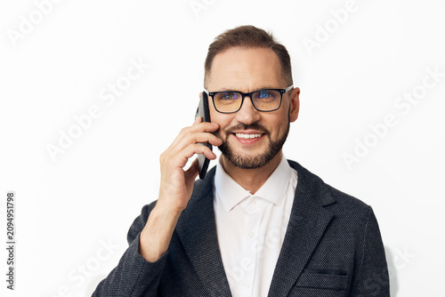 Photos A professional businessman on an isolated colored background, talking on the phone, showing confident, calm and approachable emotions