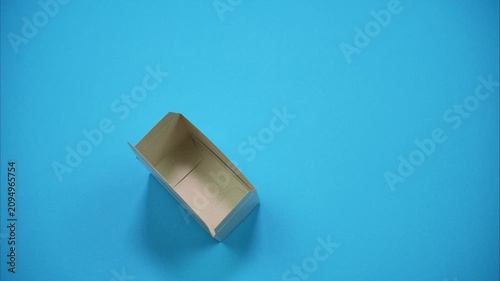 A top-view of die-cut cardboard blank transforming into a fully assembled packaging box. The paperboard template fold step by step along the crease lines. Stop-motion animation