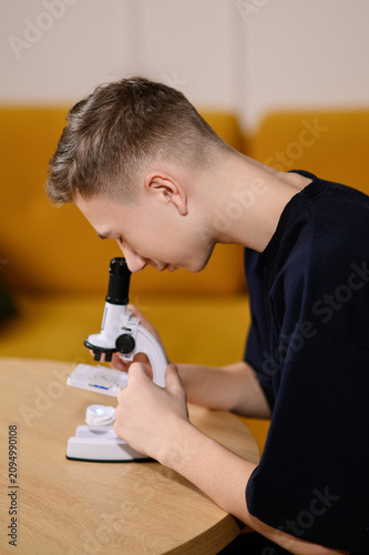 Academic research and biology olympiad preparation with high school teenage student conducting scientific microscope experiment at home STEM. School biology experiment, advanced academic research