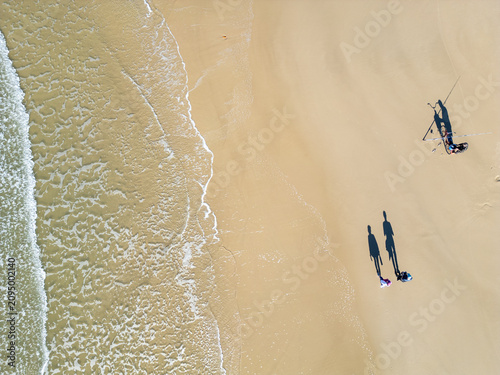 Top-Down Drone View of a Couple, a Fisherman and a Bicycle on the Beach