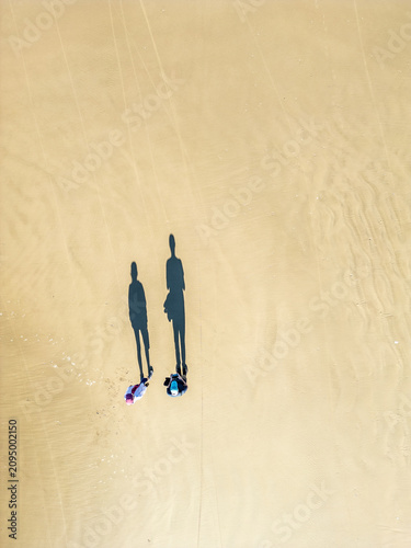 Top-Down Drone View of Couple Walking on Sand with Long Shadows