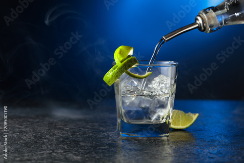 Картината върху платно Vodka with lime and ice cubes in a fogged up glass.
