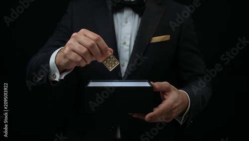 Person Places a Small Item Into a Black Box While Wearing Formal Clothing at an Event