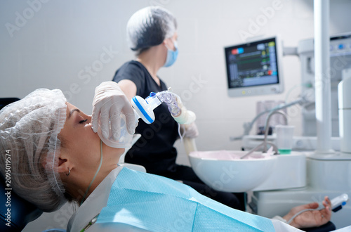 Doctor making anesthesia while female patient lying in dentist chair