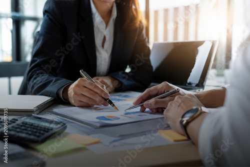 Business professionals analyzing financial charts and documents together in modern office meeting