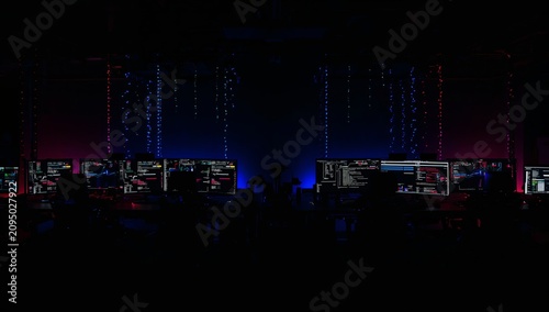 Workstation Setup With Multiple Monitors in Dark Room With Colorful Lights at...