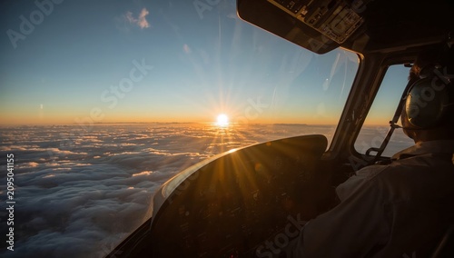 Pilot Works in Cockpit During Sunset Above the Clouds Near a Skyline