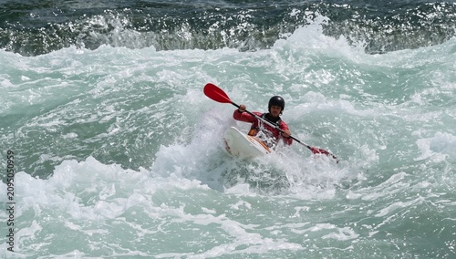Kayaker Navigates Fast River Waters on a Sunny Day Near Rocky Banks