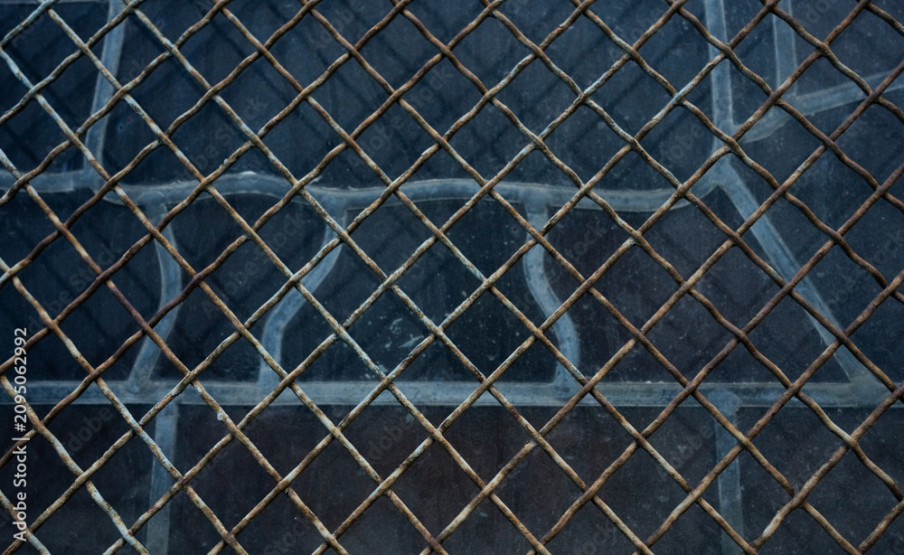 Fototapeta premium Full frame horizontal shot of rusty wire mesh fence over dark glass window