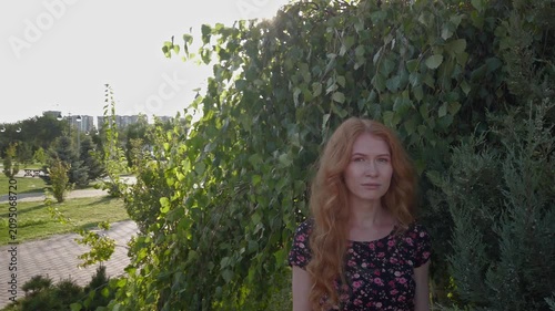 Botanical Garden Portrait: Elegant Woman with Copper Hair Amidst Lush Greenery