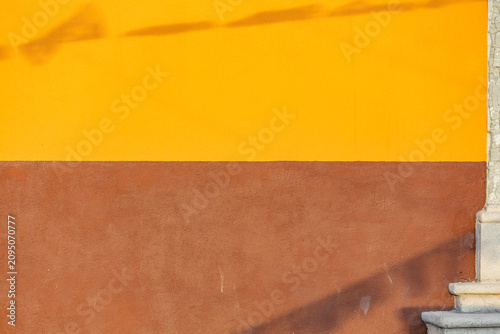 Canvastavla A two-toned wall, with the top half painted a vibrant yellow and the bottom half a rich brown, stands as a backdrop