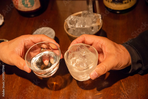 Men toasting with sake cups filled with ice water on a wooden table during celebration