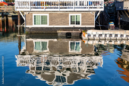 Quadro su tela A houseboat is reflected in the water, showcasing its unique architecture and waterfront living